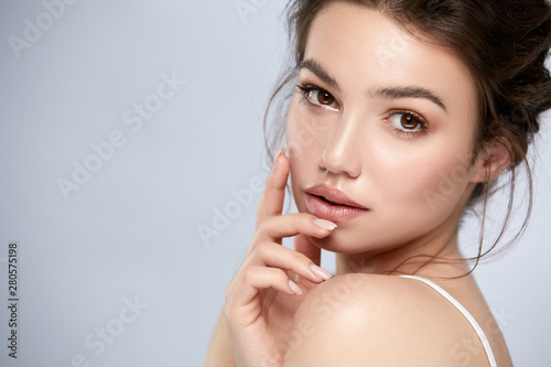 elegant woman portrait with natural make-up and golden lips on grey