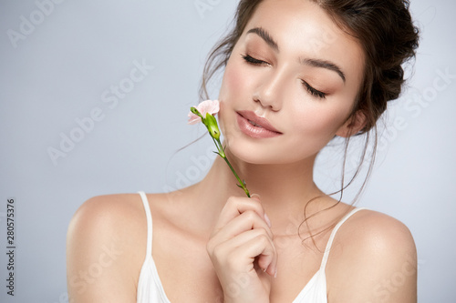 cute girl with perfect skin and white flower near face closed eyes
