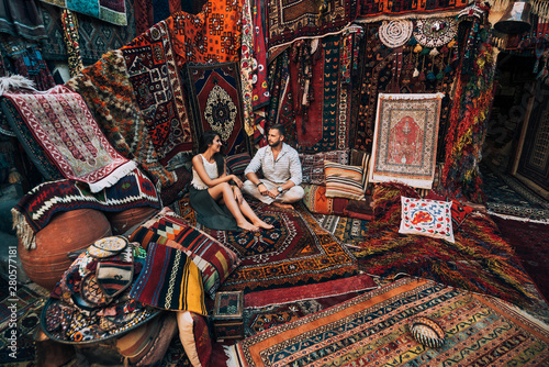 Couple travels the world. Happy couple in the store. Couple in love in Turkey. Man and woman in the Eastern country. Gift shop. Persian shop. Tourists in store. Oriental carpet. Istanbul. Cappadocia