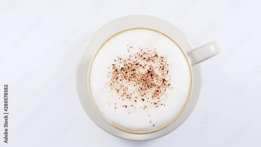 Hot coffee cup with frothed milk foam and chocolate decoration rotating on white background. Top view Hot coffee cup with frothed milk foam and chocolate decoration rotating on white background. Top view