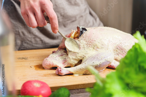 Close-up of female hands preparing duck or goose for baking. White carrot dressing with mayonnaise. Christmas dish duck goose with apples