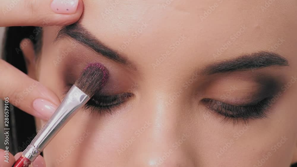 Professional stylist make-up artist makes eye makeup model Professional stylist make-up artist makes eye makeup model