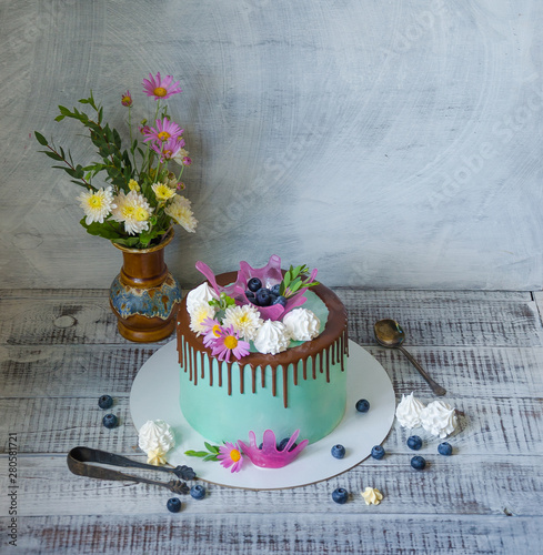 tasty chocolate drip cake decorated with zephyr and flowers photo