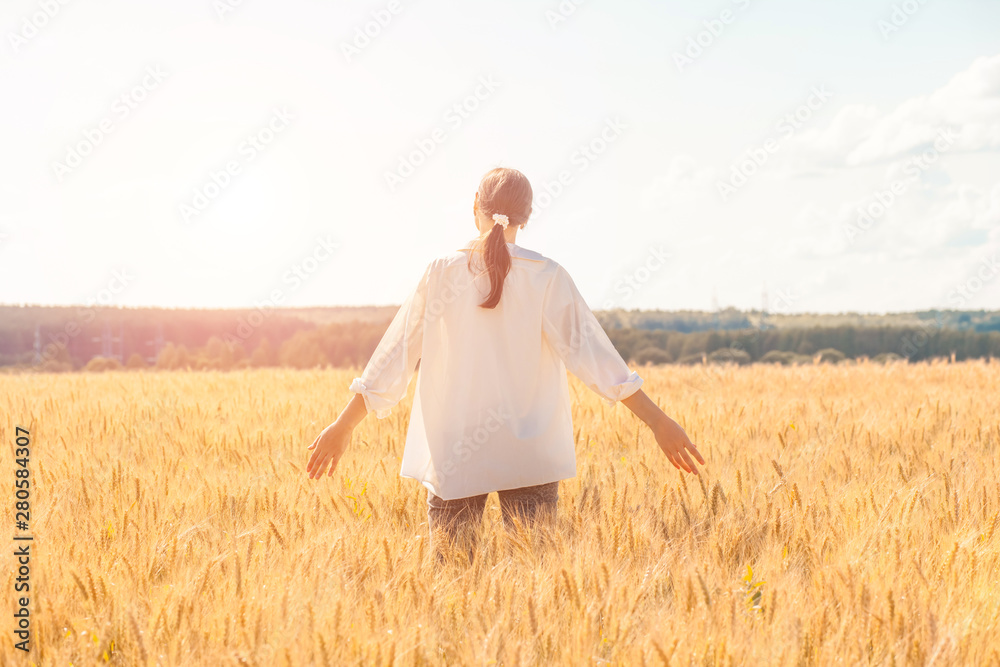 Young woman with hands up in wheat field in summer Young woman with hands up in wheat field in summer