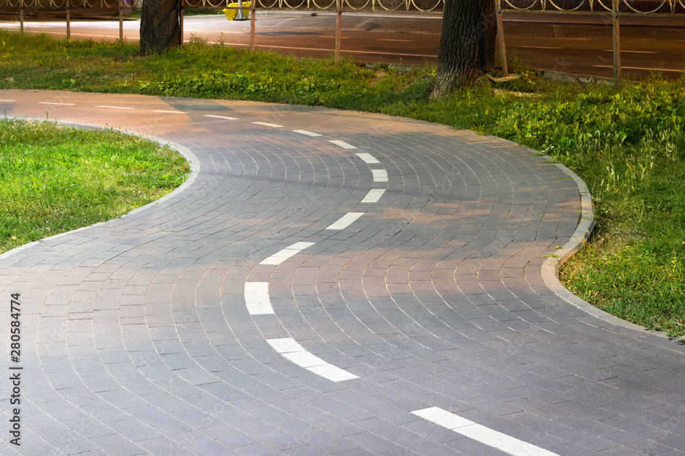 Obraz premium Tiled bike path. Curving sidewalk. Winding road.