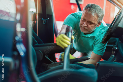 Man cleaning the interior of his car with vacuum cleaner
