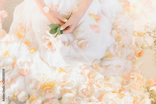 girl in a wedding dress sits in flower petals