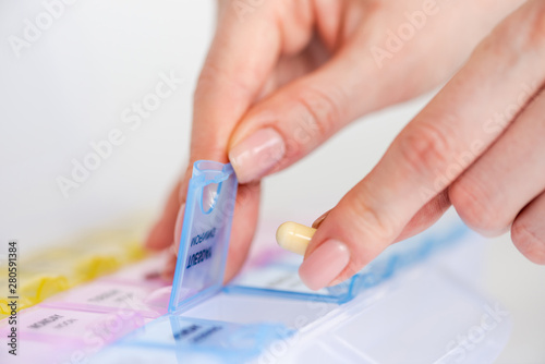 Woman's hand opening a pill organizer box photo