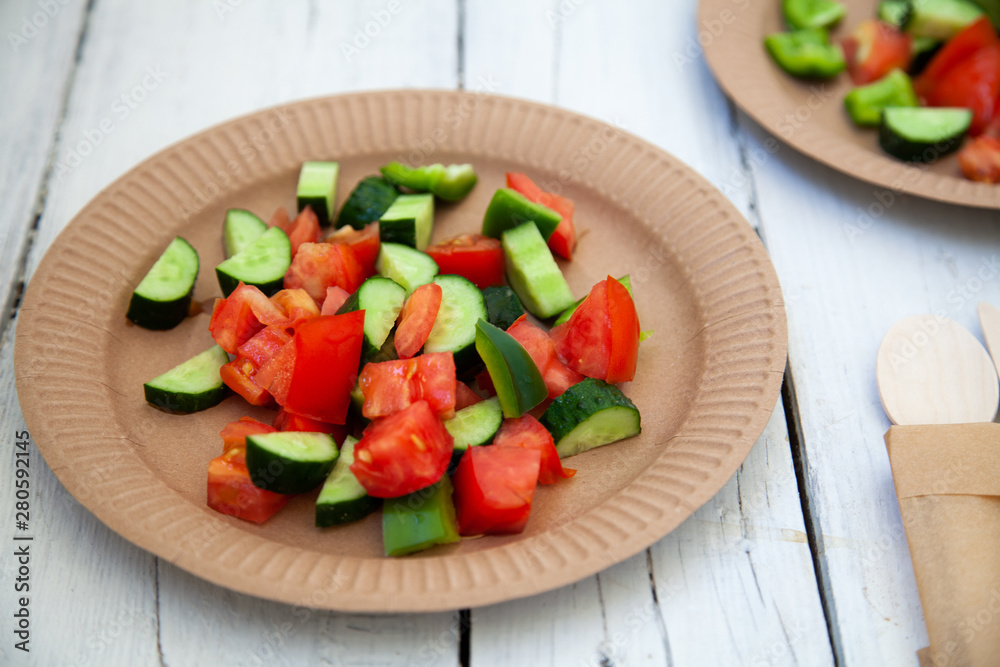 paper cardboard dishes with vegetable salad tomatoes cucumbers with wooden devices fork knife horse