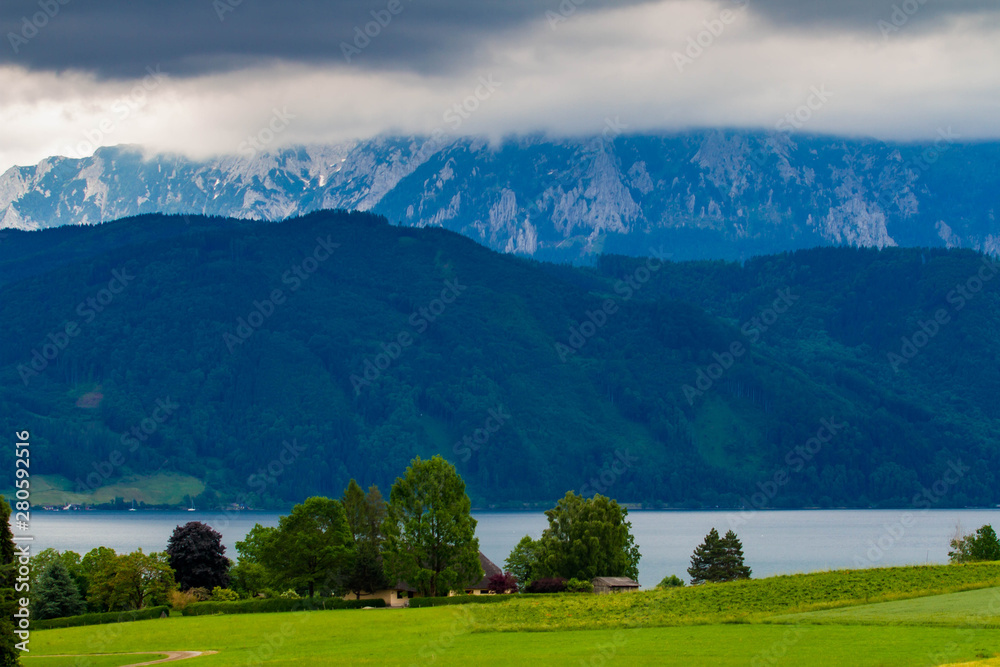 Calm cloudy day on lakefront of Attersee with mountains in background in late summer. lake Attersee in the Austrian Salzkammergut