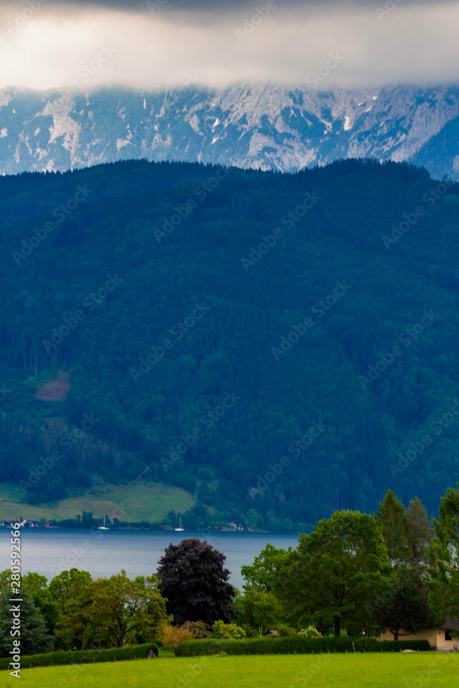 Calm cloudy day on lakefront of Attersee with mountains in background in late summer. lake Attersee in the Austrian Salzkammergut