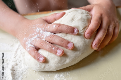 Closeup portrait of kid hands making dough for pastry 