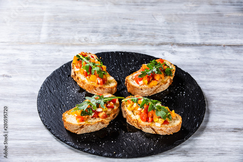 Bruschettas on black stone plate on wooden background