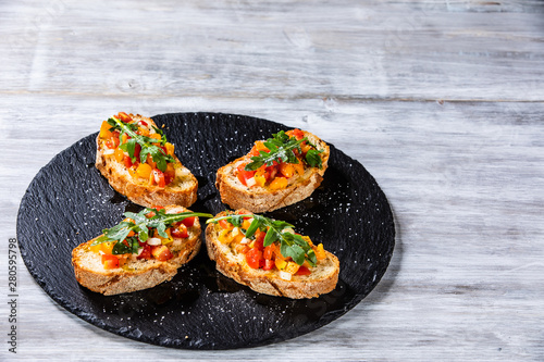 Bruschettas on black stone plate on wooden background