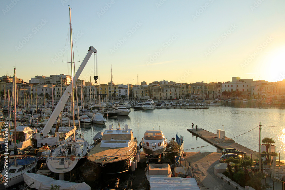 Boats and yachts in the quiet port of Trani in Puglia Italy, during sunset.