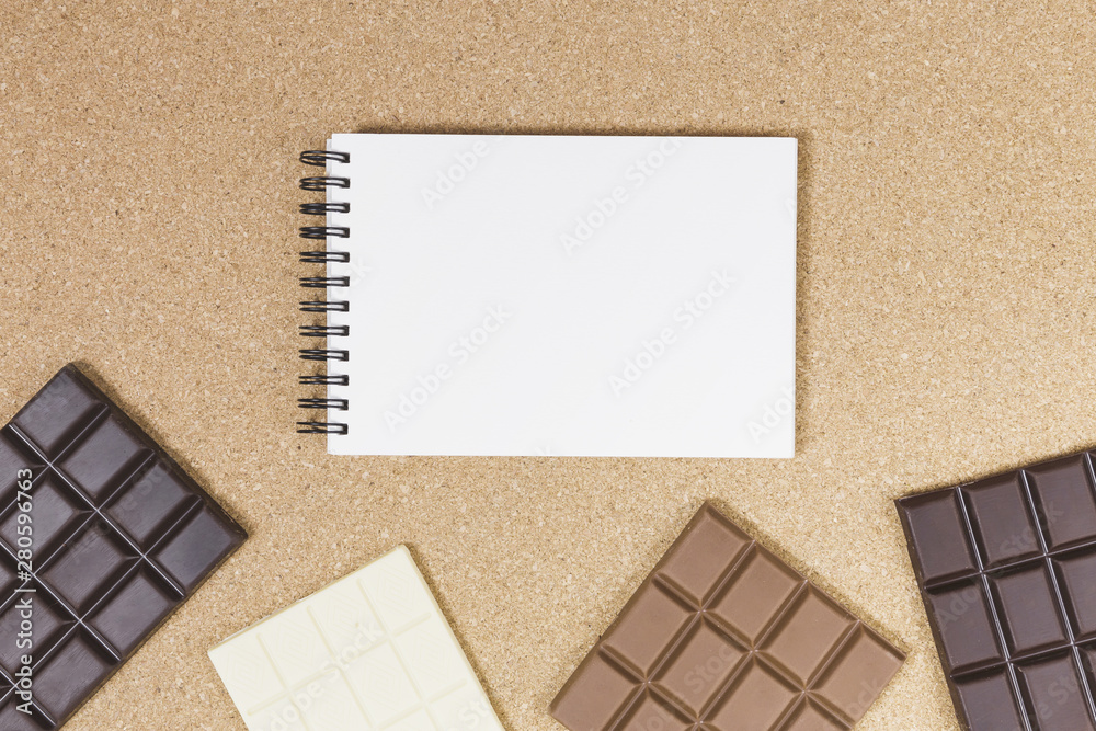 Fototapeta premium Top view chocolate bars with notebook