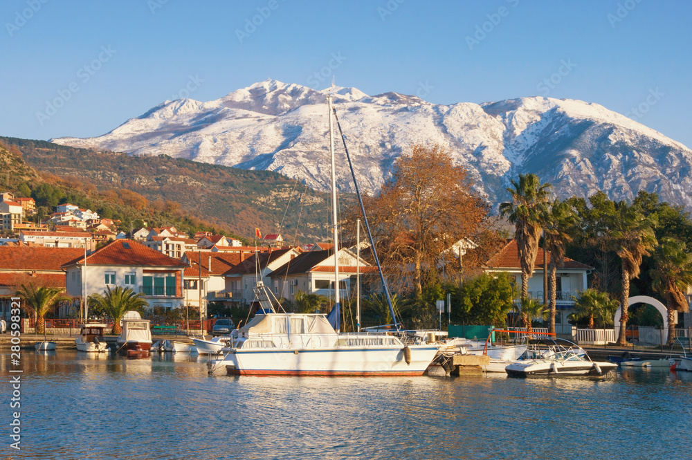 Picturesque winter Mediterranean landscape.  Montenegro, Adriatic Sea, Bay of Kotor. View of Marina Kalimanj in Tivat city and  snow-capped mountains of Lovcen