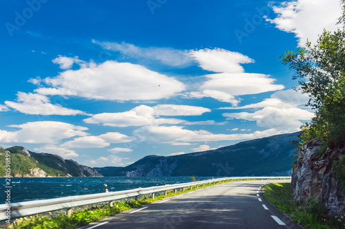 Picturesque view through the car window to empty road and natural landscape in Nordland County, Northern Norway. Norwegian fjord landscape in summertime. Motion blur, selective focus on the center