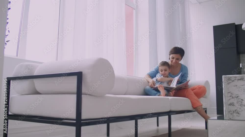 Mother and son read books. Happy young mother and son read books on the sofa at home. Mother and son read books. Happy young mother and son read books on the sofa at home.