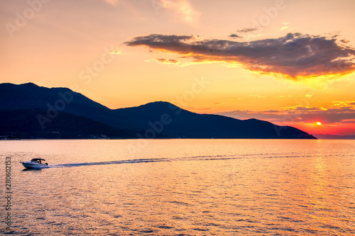 boat to the sea at sunset in the background of mountains and sun beams, run from Keramoti city to Thassos island in Greece