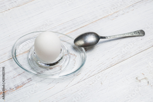 Boiled soft-boiled chicken egg on a white wooden background.