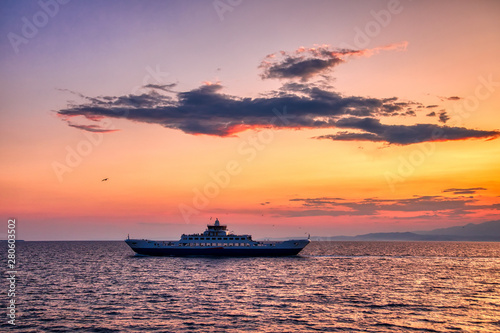 Ferry boat to the sea at sunset in the background of mountains and sun beams, run from Keramoti city to Thassos island in Greece