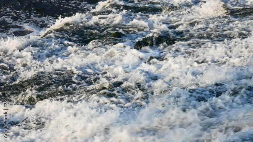 Fast flowing water gushing over rocks in the river. Close up. Fast flowing water gushing over rocks in the river. Close up.