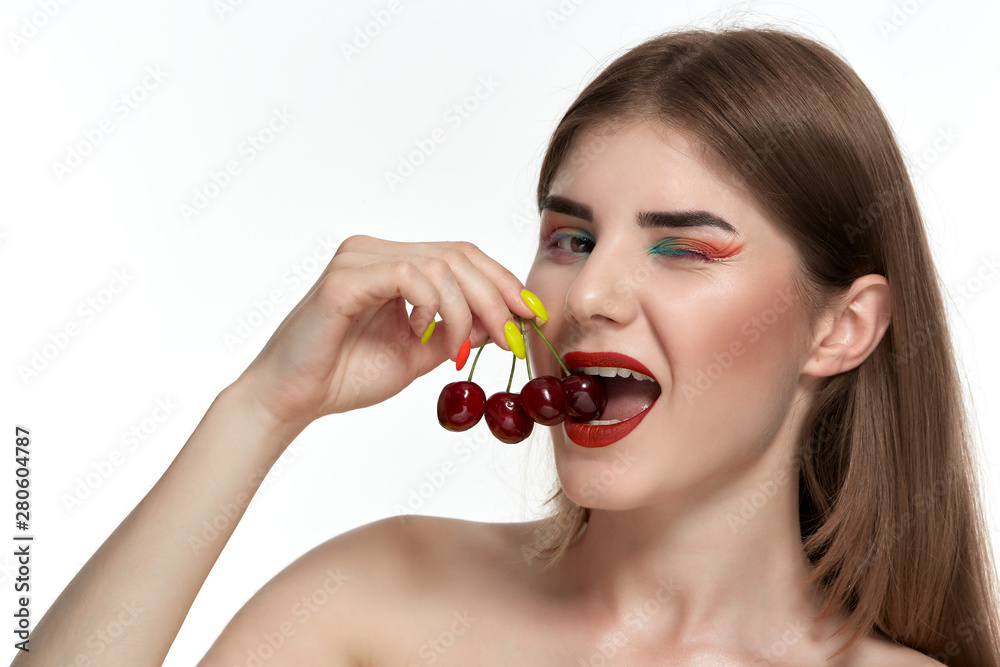 Closeup portrait of a beautiful young woman with bright color make-up holding strawberry near the face. Closeup portrait of a beautiful young woman with bright color make-up holding strawberry near the face.