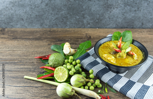 Green curry (Kaeng kheiyw hwan) with Thai food for steamed rice or rice noodles. chicken green curry is thai food very popular on dark wooden background. top view photo