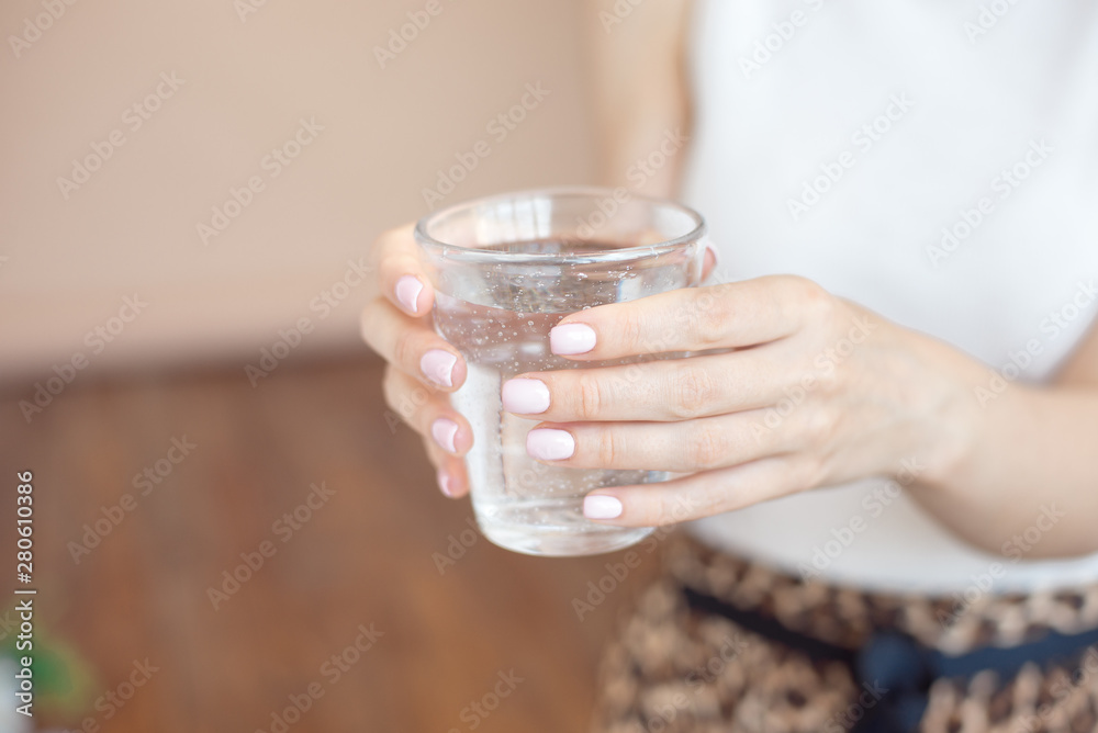 Female hands holding a clear glass of water.A glass of clean mineral water in hands, healthy drink Female hands holding a clear glass of water.A glass of clean mineral water in hands, healthy drink
