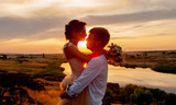 a loving couple, a guy and a girl kiss and hug at sunset on a mountain against the background of the river