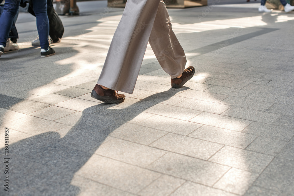 Photo of human legs in different shoes walking on the sidewalk on the street Photo of human legs in different shoes walking on the sidewalk on the street