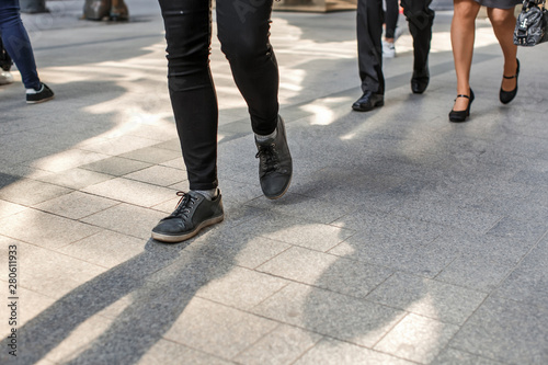 Photo of human legs in different shoes walking on the sidewalk on the street © Viktor Domin
