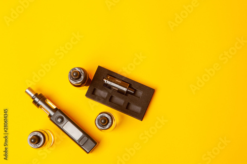 Vape and liquid on a yellow background. Electronic Cigarette. Accessories for smoking E-cigarettes. Smoking gadgets. Set for vaping. Vape conception