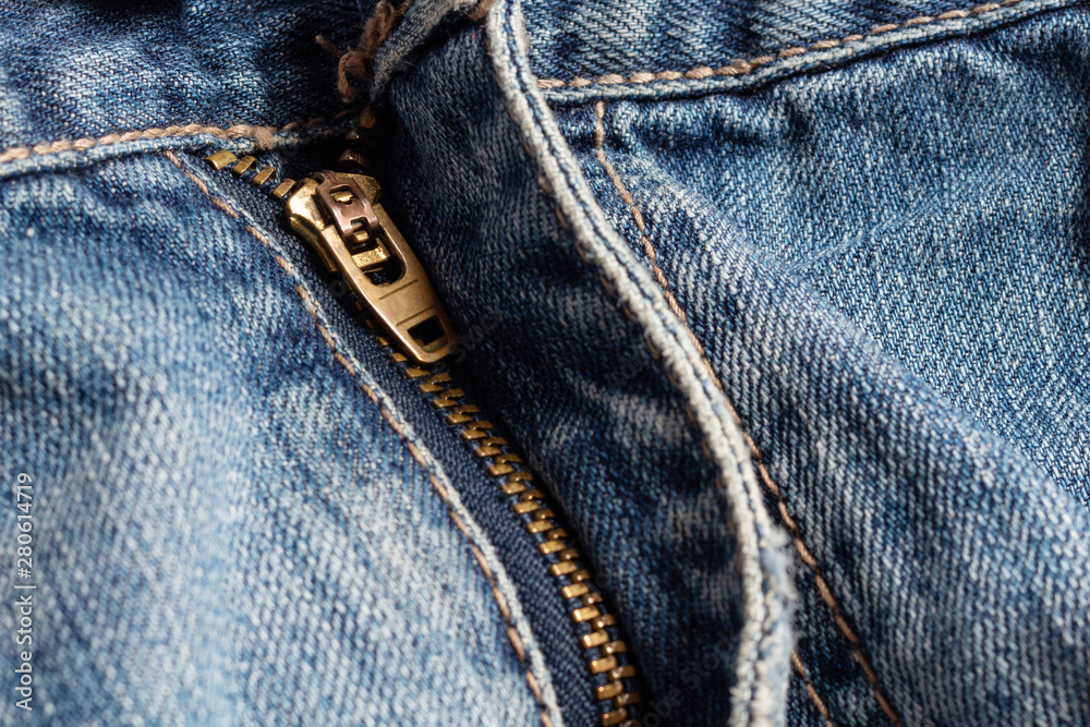 Metal stained brass zipper with slider blue denim background close up selective focus handmade sewing tailoring Metal stained brass zipper with slider blue denim background close up selective focus handmade sewing tailoring