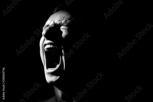 Fototapeta black and white photo on a black background, distorted face screaming