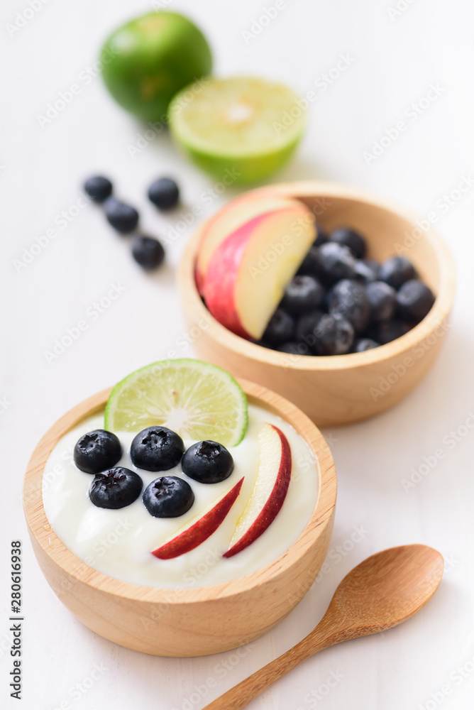Yoghurt eating with blueberry, apple and lime on white background, healthy food