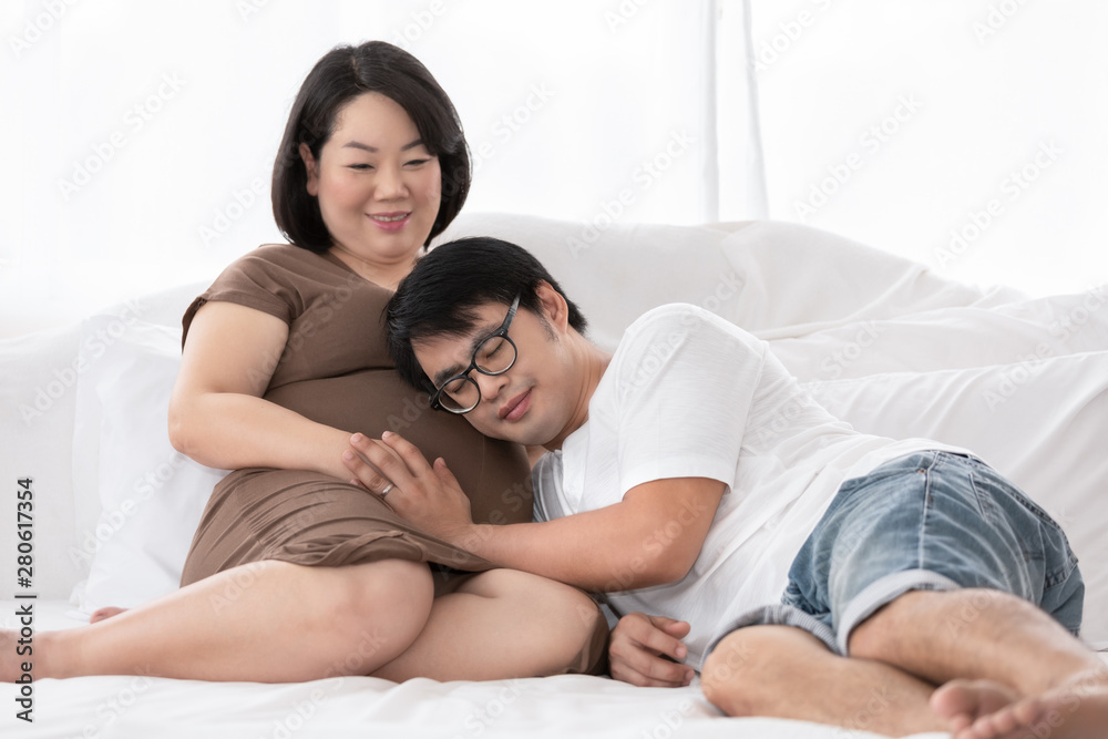 pregnant woman and her husband happy smiling while spending time together in the bedroom on white bed pregnant woman and her husband happy smiling while spending time together in the bedroom on white bed