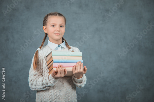 Closeup portrait of a a smart girl embracing her books, isolated on grey backgrounds. photo
