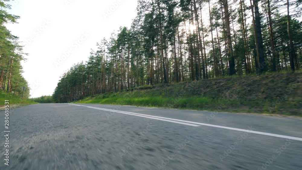 Motorcycle driver is doing a stunt while moving. Biker riding down country road. Motorcycle driver is doing a stunt while moving. Biker riding down country road.