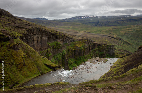 View from the top of Glymur waterfall. Green hills  high waterfall. Iceland