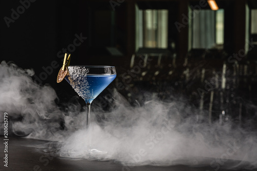 Aviation  drink with gin  lemon juice maraschino liqueur and violette cream liquor. Garnished with lime chips and coconut crumbles. Place for text copy-paste on a black background and smoke for mystic