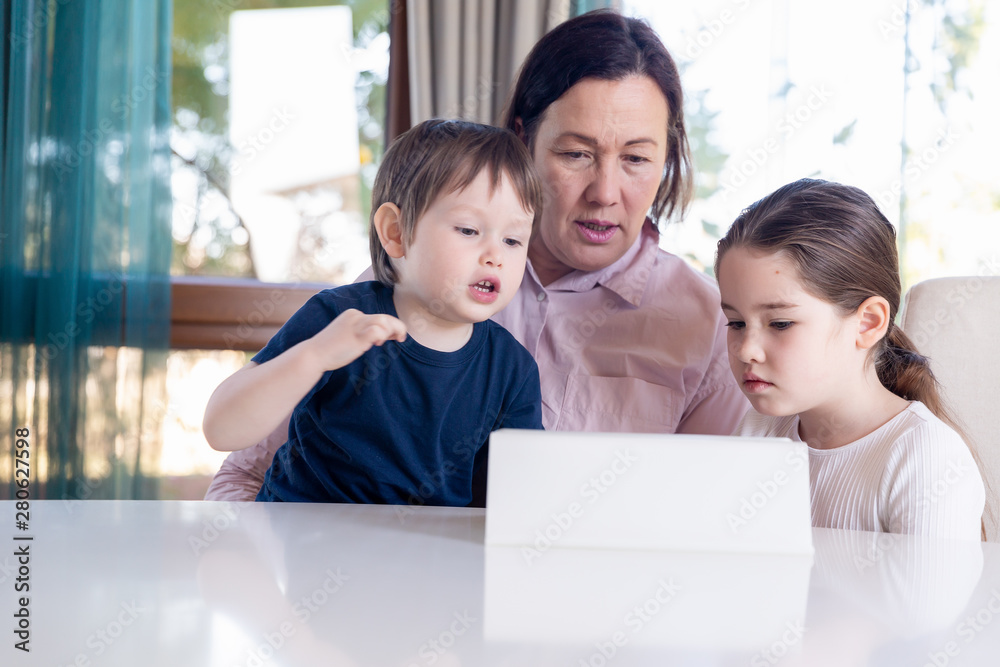 Grandma entertaining her little grandchildren with a tablet computer game Grandma entertaining her little grandchildren with a tablet computer game