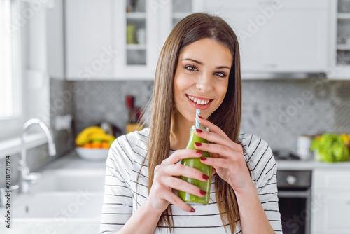 Beautiful happy woman sitting with drinks and healthy green food at home. Vegan meal and detox concept