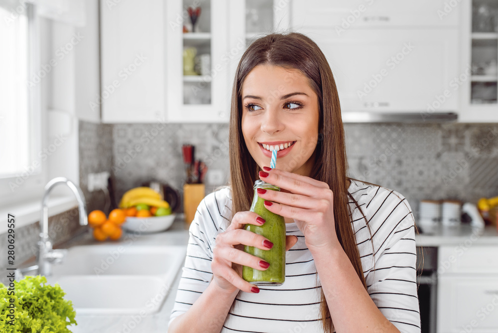 Happy woman drinking green juice or shake at home Happy woman drinking green juice or shake at home