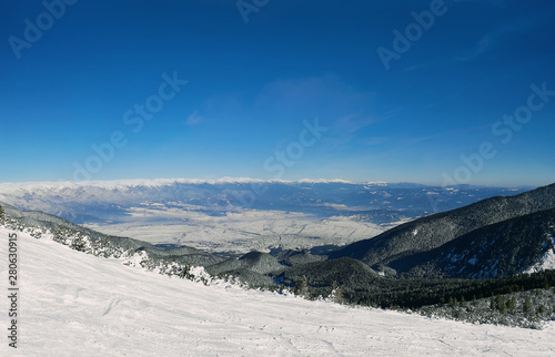 Ski slope and panorama of winter mountains. Alpine ski resort Bansko, Bulgaria
