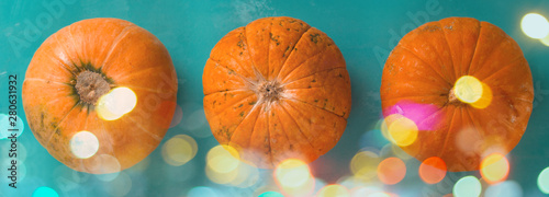 top view flat lay three pumpkins on a blue background with shiny bokeh banner