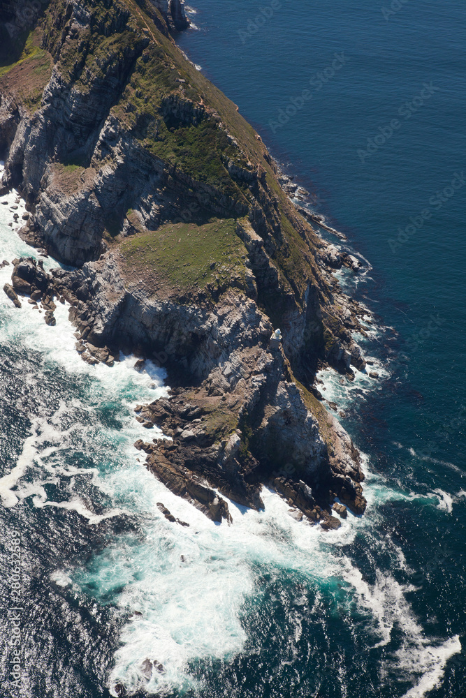 Aerial view of Cape point with lighthouse and Cape of Good Hope from a helicopter. Panorama of South Africa from birds eye view on a sunny day. Edge of the earth from helicopter view.