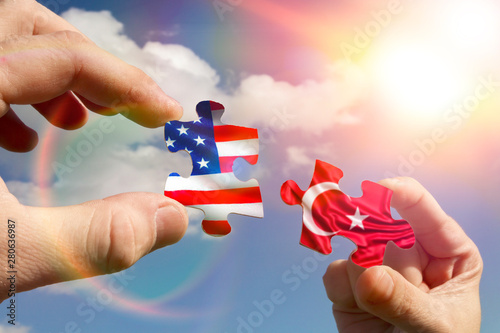 Foto Two hands assemble a puzzle with the flags of Turkey and America