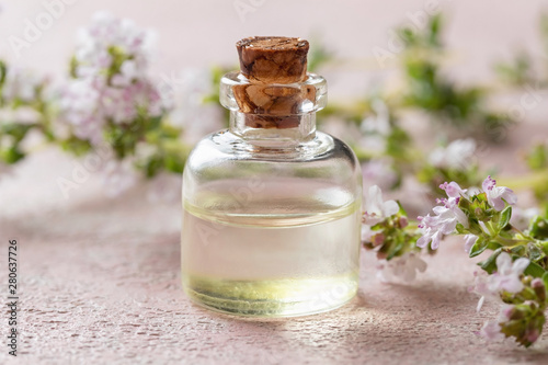 A bottle of thyme essential oil with blooming thyme
